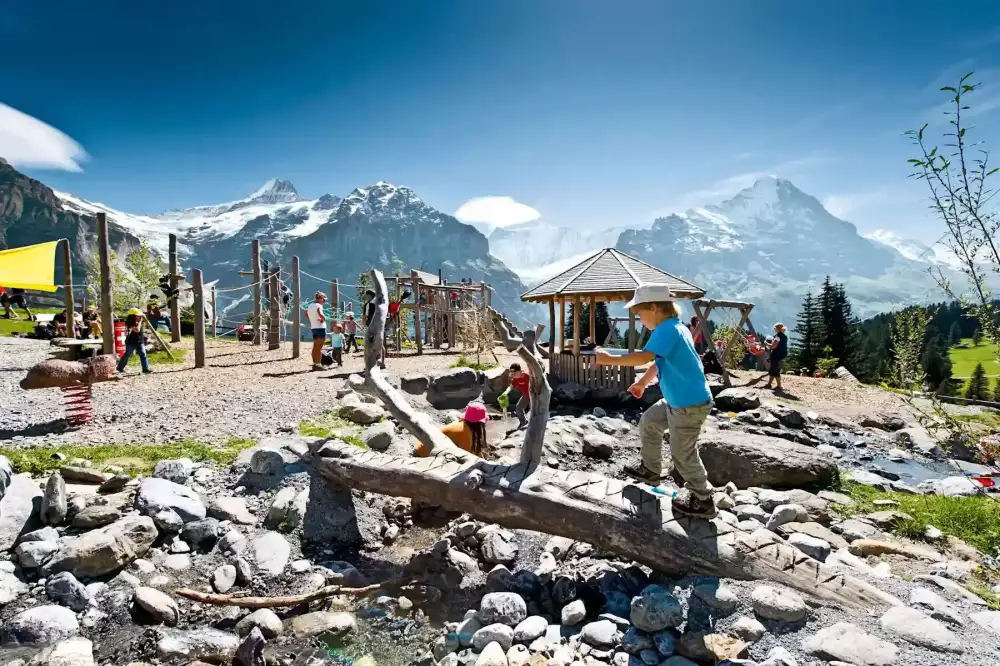 grindelwald-first-alpenspielplatz-kleiner-bach-mit-Kindern-nebendrann